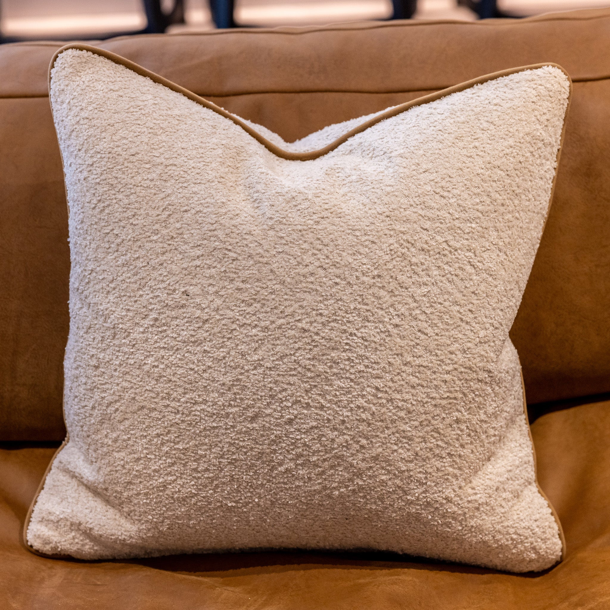 Luxury boucle cushion in ecru with a tan coloured piping. A plump feather inner cushion is included. Our made to order cushions are plump and cosy. Dimensions: 500 x 500 mm Made to order in approx 3 weeks